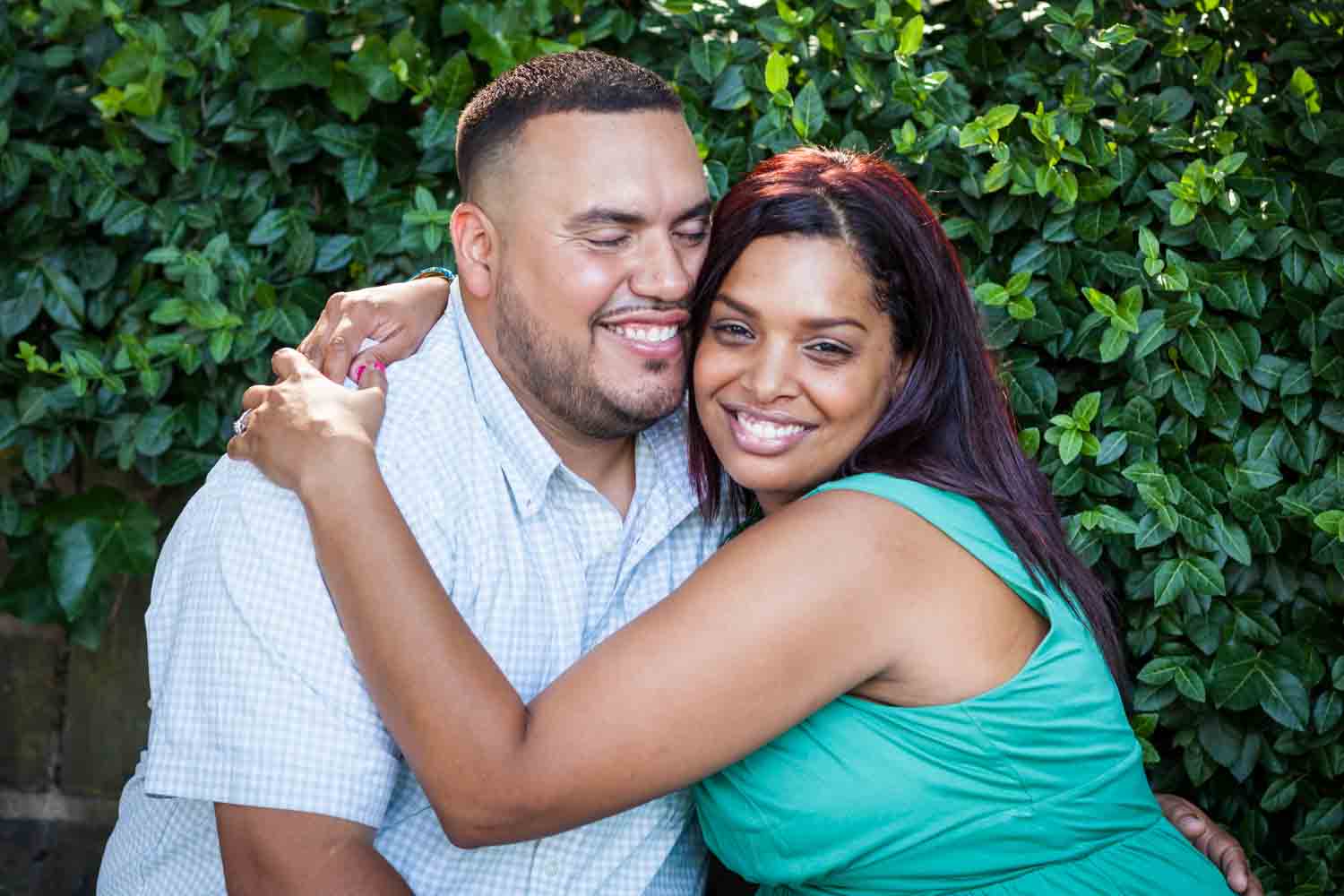 Couple hugging in front of bush during a Central Park engagement shoot