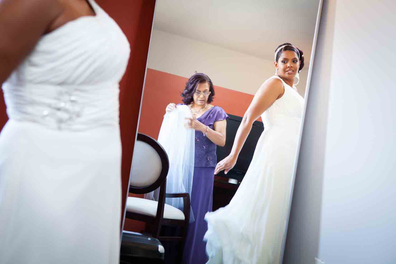 Bride looking at reflection of white dress in mirror