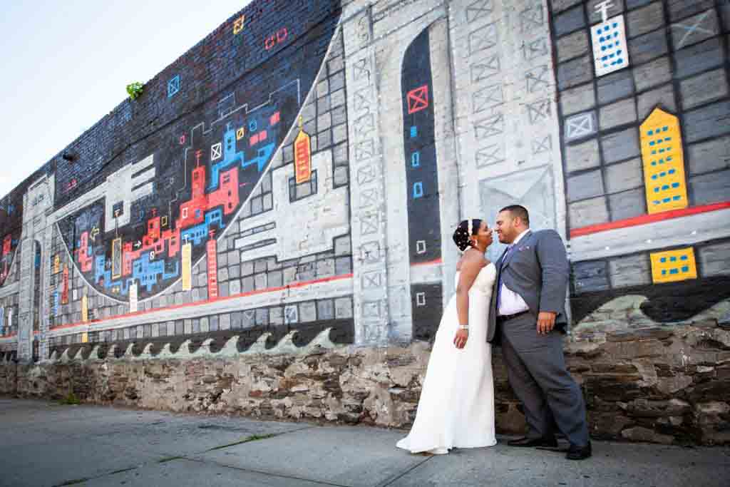 Bride and groom standing in front of colorful graffiti mural before their Attic Studios wedding