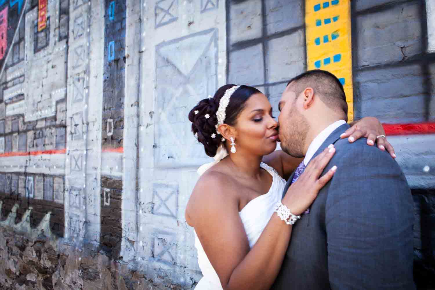 Bride and groom kissing in front of graffiti mural