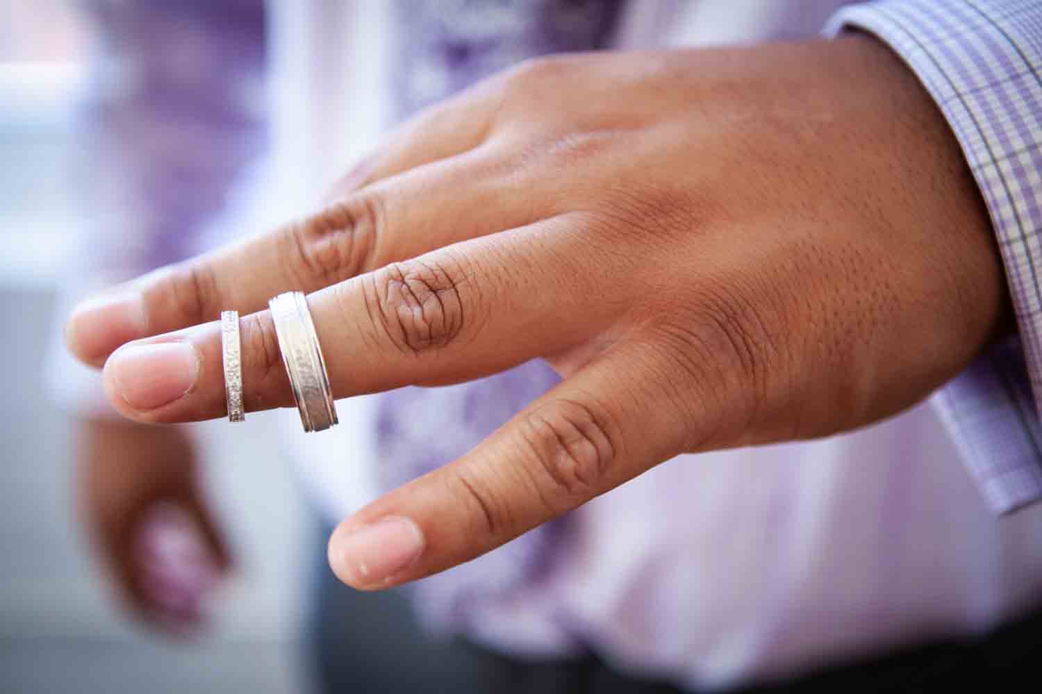 Close up on man's hand holding wedding rings on finger