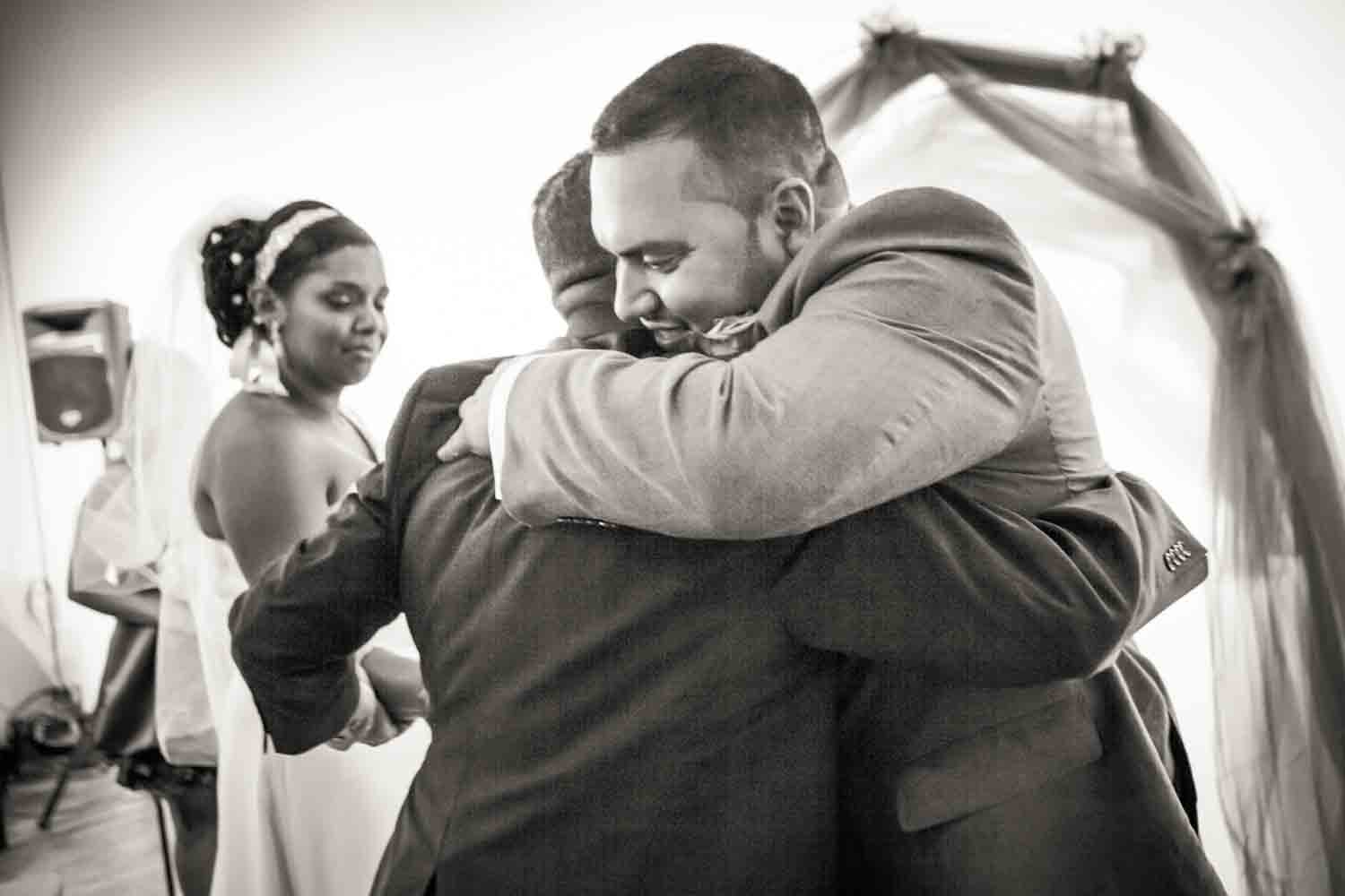 Black and white photo of groom hugging bride's father 