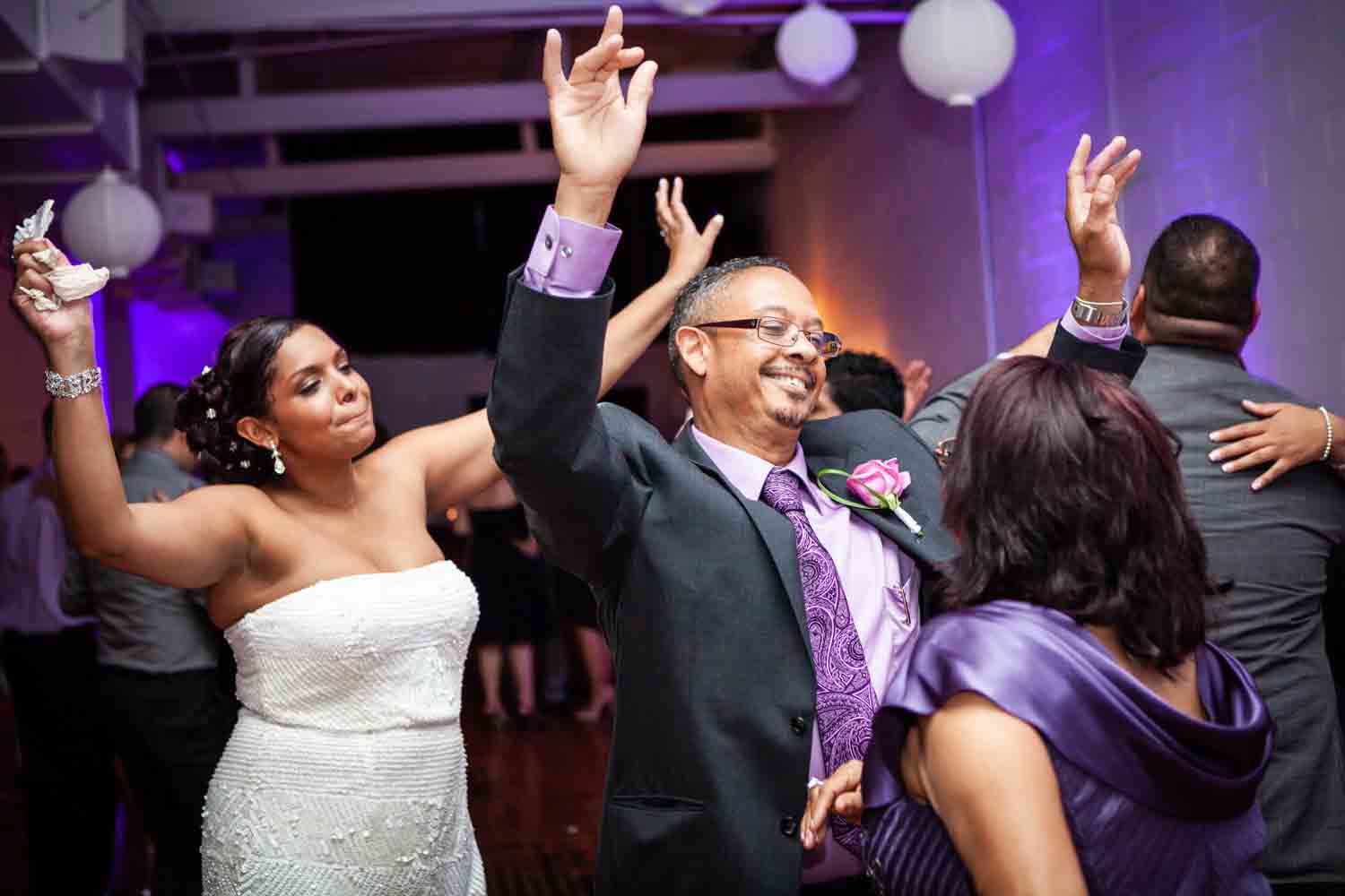 Man dancing in between two women at a wedding reception