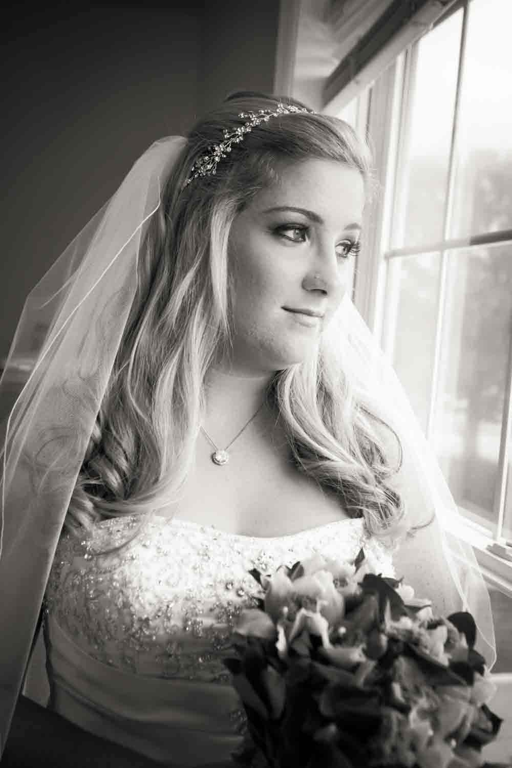 Black and white portrait of bride at window