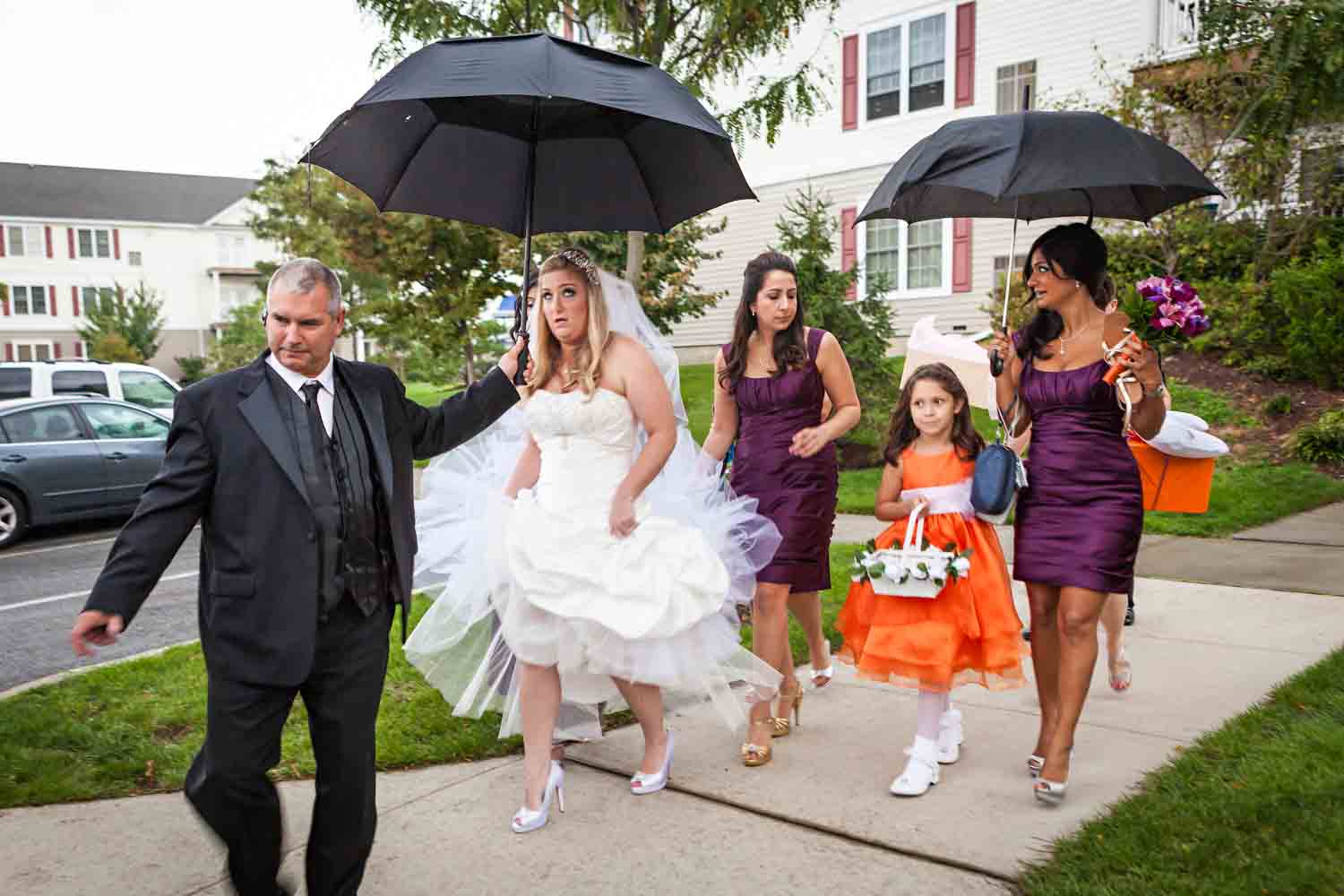 Bride and bridal party walking under umbrellas