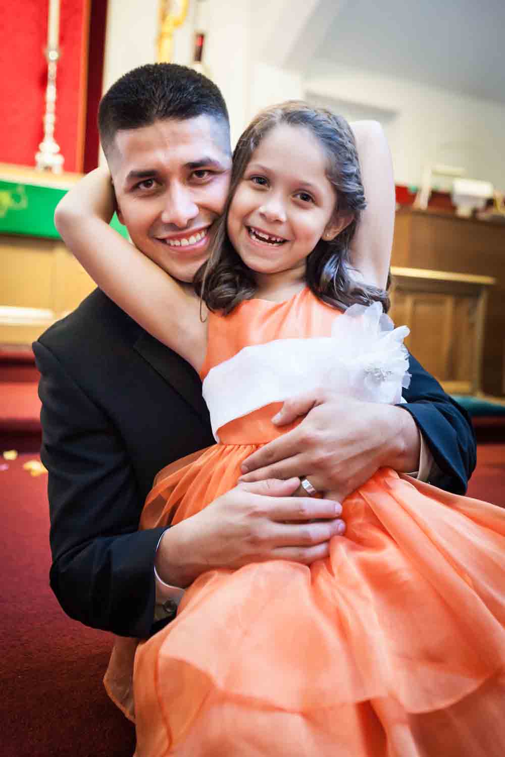Groom and little girl wearing orange dress smiling