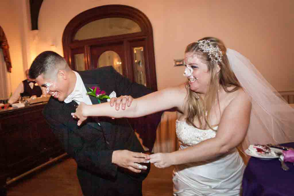 Bride smashing cake into groom's face at a Fort Hamilton Community Center wedding