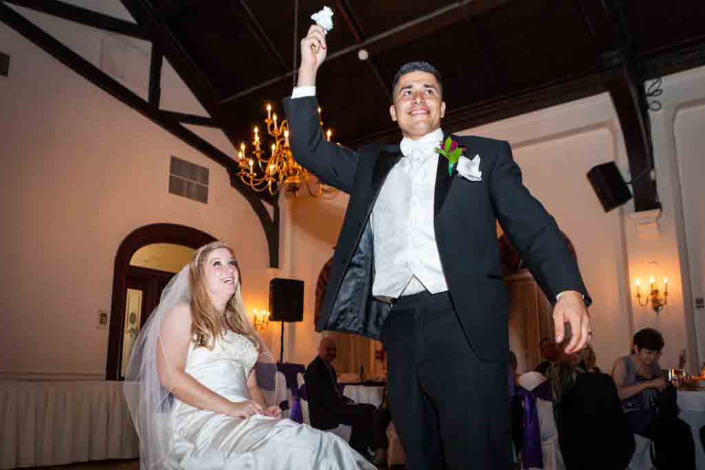 Groom holding up garter at a Fort Hamilton Community Center wedding