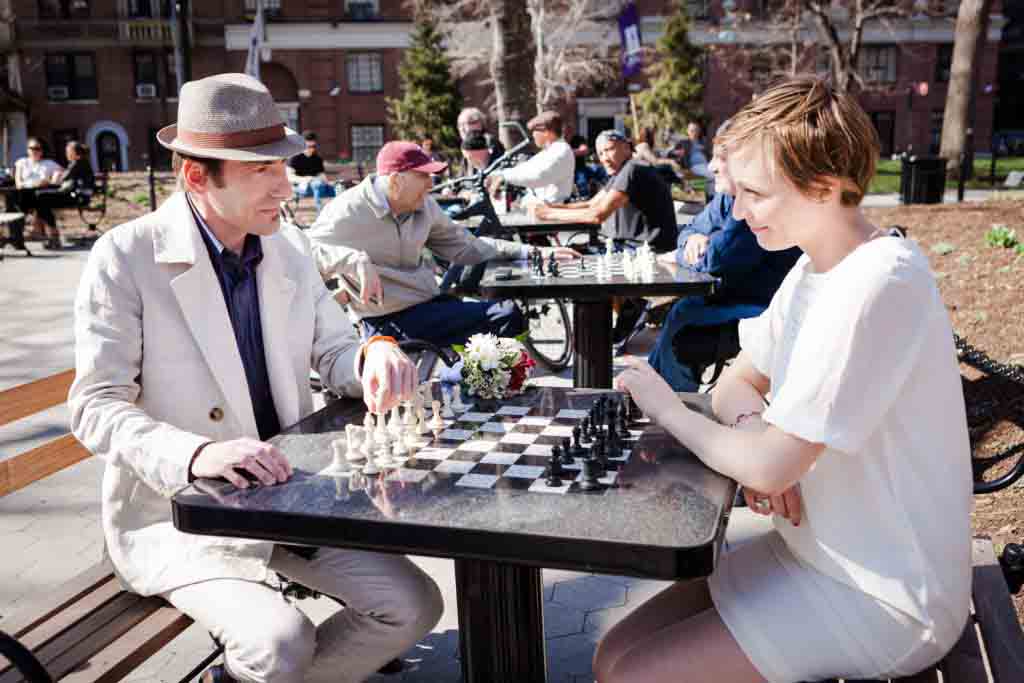 Couple playing chess with other players in the background