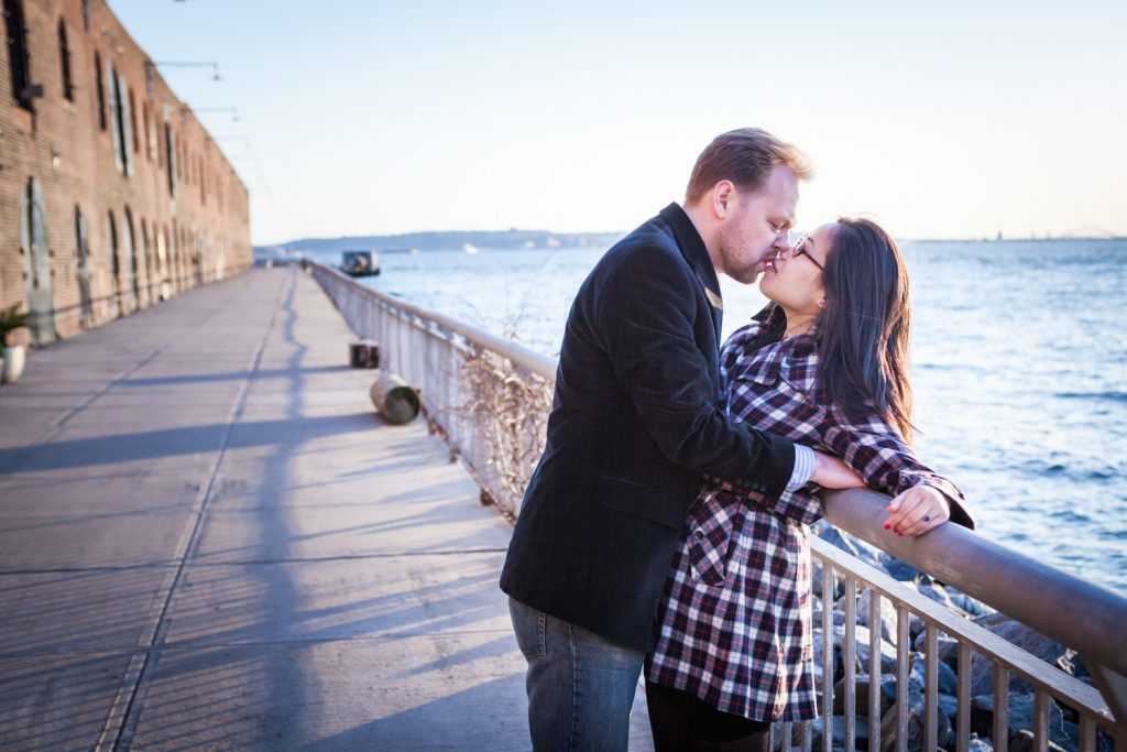 Red Hook engagement photos of couple kissing against railing