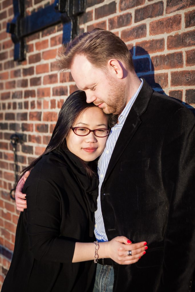 Red Hook engagement photos of couple in front of brick wall