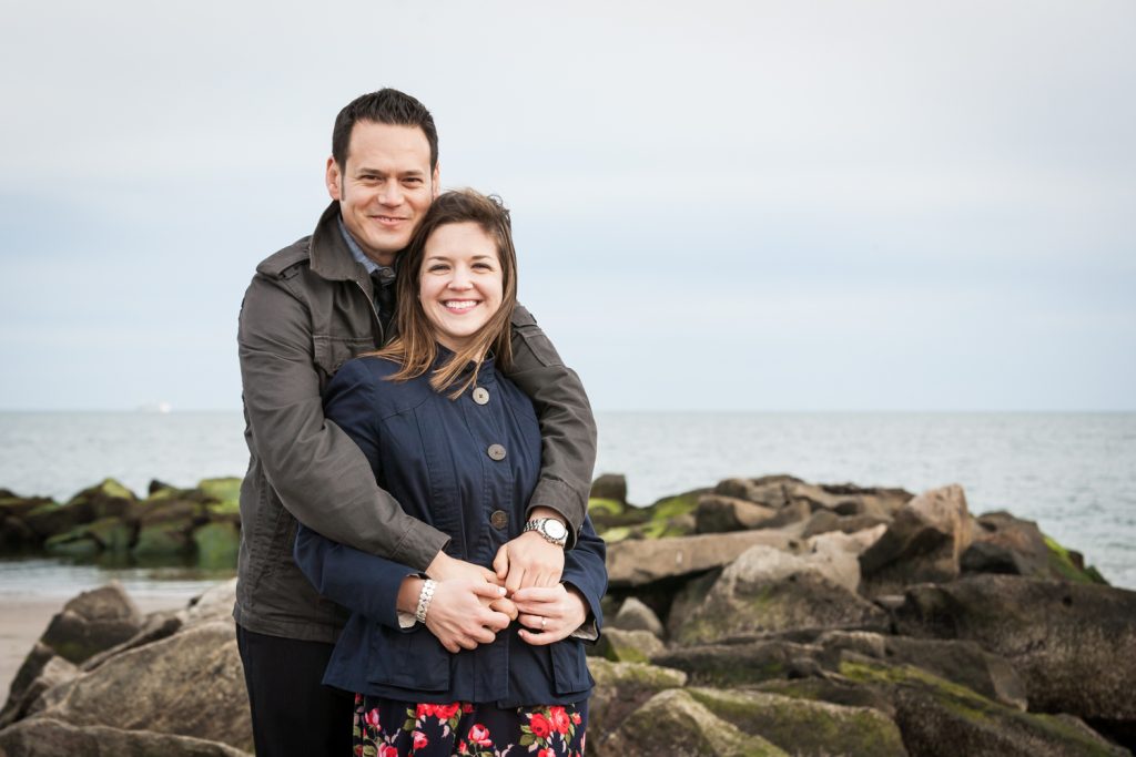 Couple sitting on rock by beach for an article on Coney Island engagement photo tips