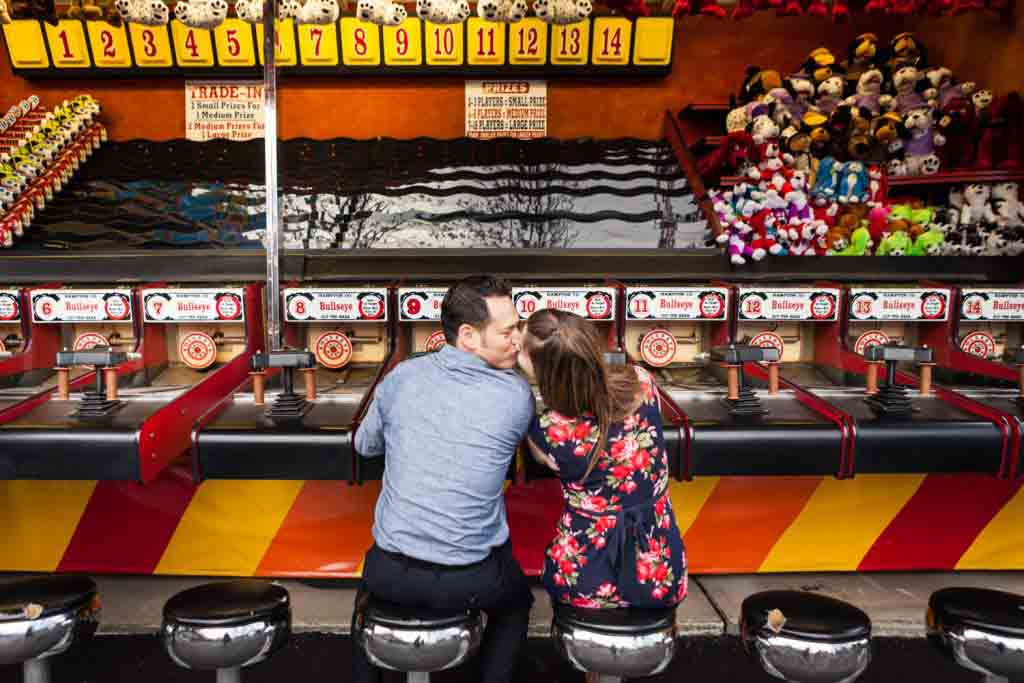 Couple kissing in front of carnival game at Coney Island