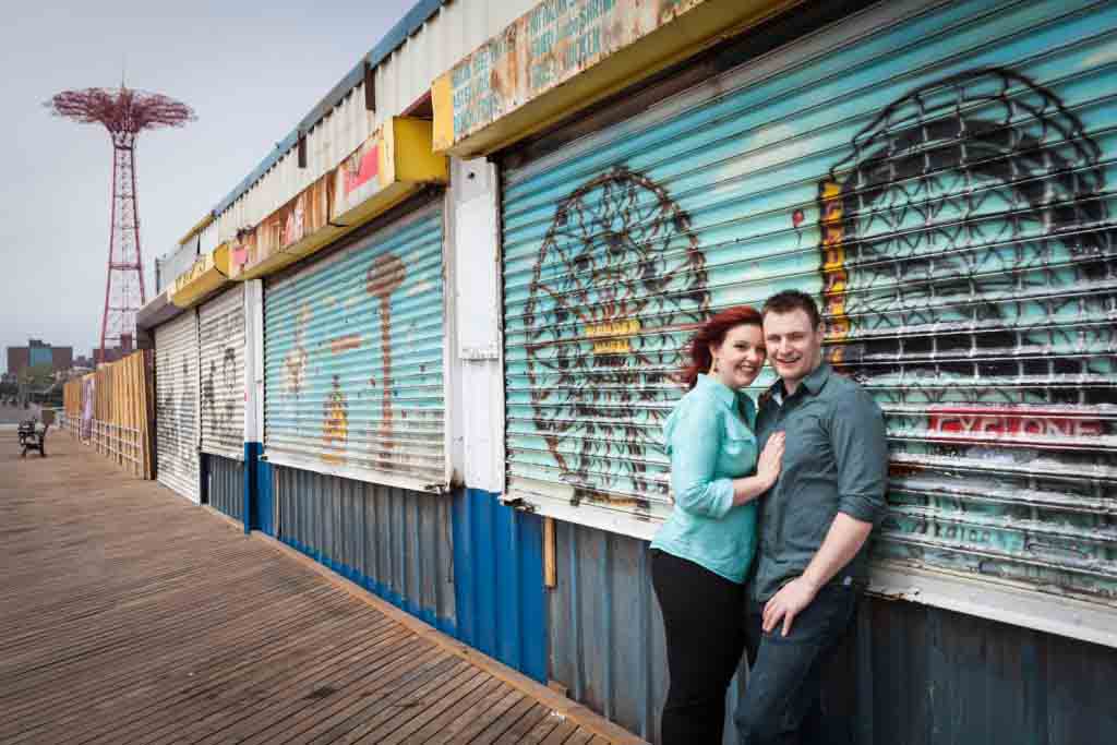 Coney Island engagement photos of couple leaning against colorful metal gate