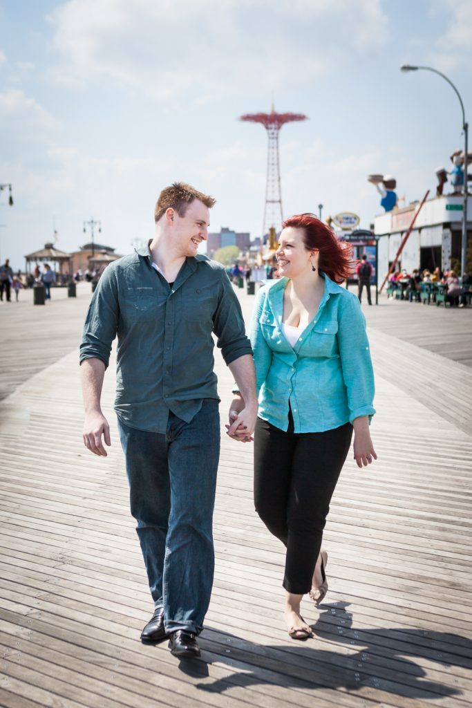 Coney Island engagement photos of couple walking on boardwalk