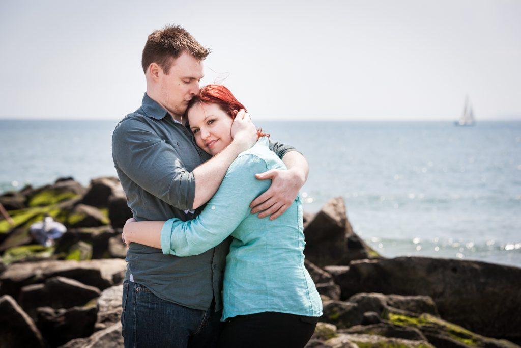 Coney Island engagement photos of couple standing on rock