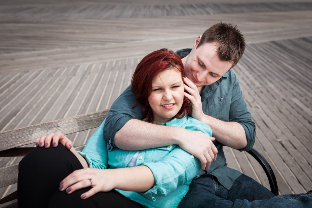 Coney Island engagement photos of woman leaning on man on a bench