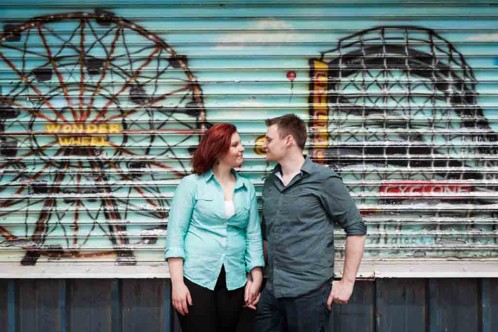 Coney Island engagement photos of couple in front of colorful metal gate