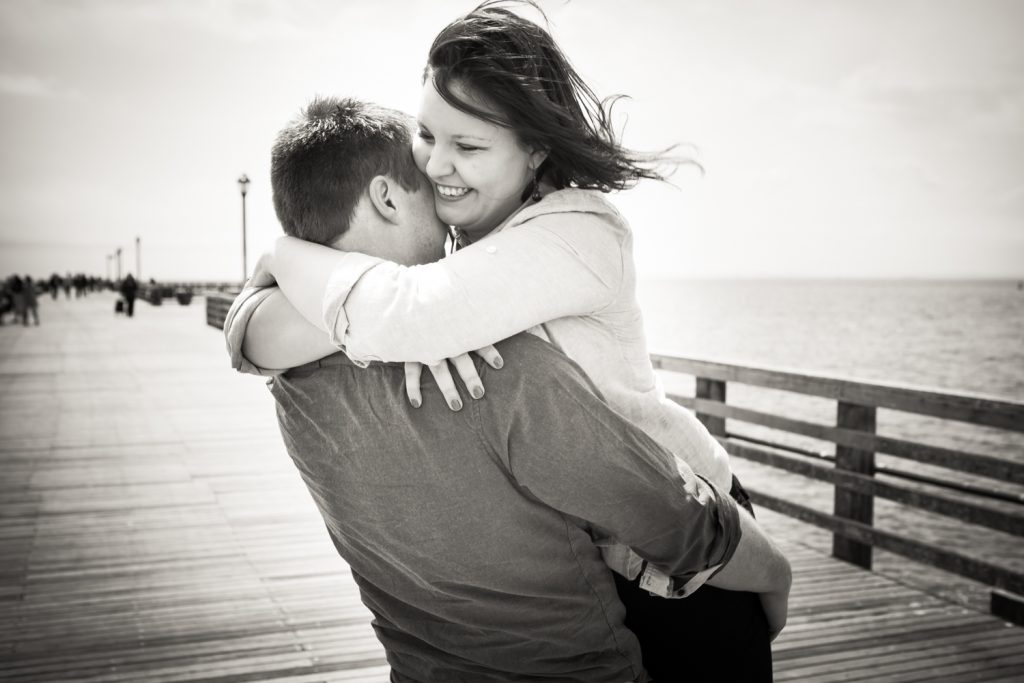 Black and white photo of man lifting up woman on Coney Island boardwalk