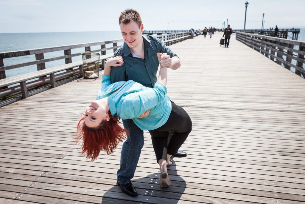 Coney Island engagement photos of couple dancing on boardwalk
