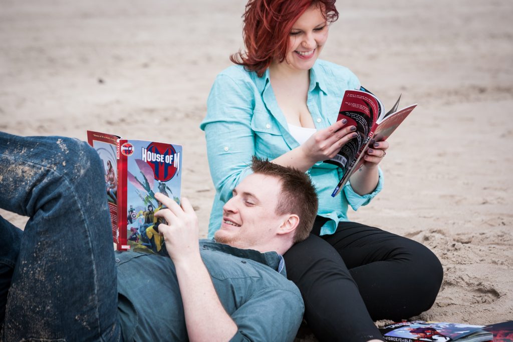 Coney Island engagement photos of couple reading comic books on beach