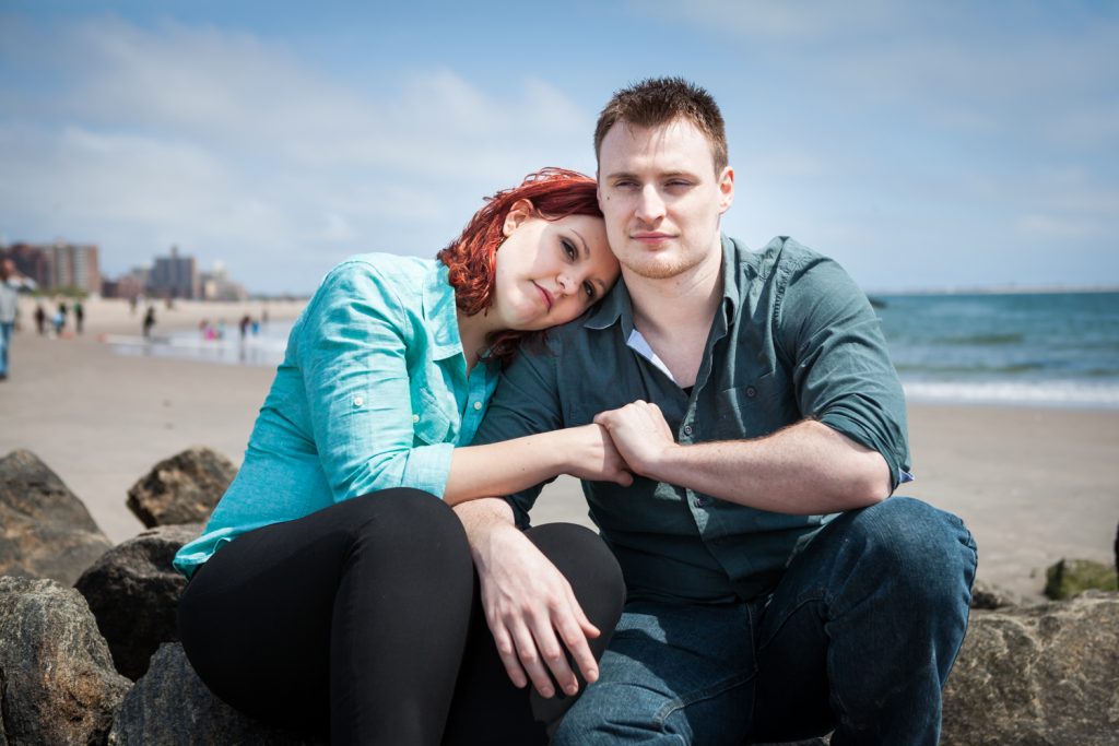 Coney Island engagement photos of couple sitting on rock