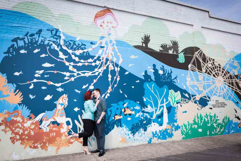 Couple hugging against colorful New York Aquarium mural