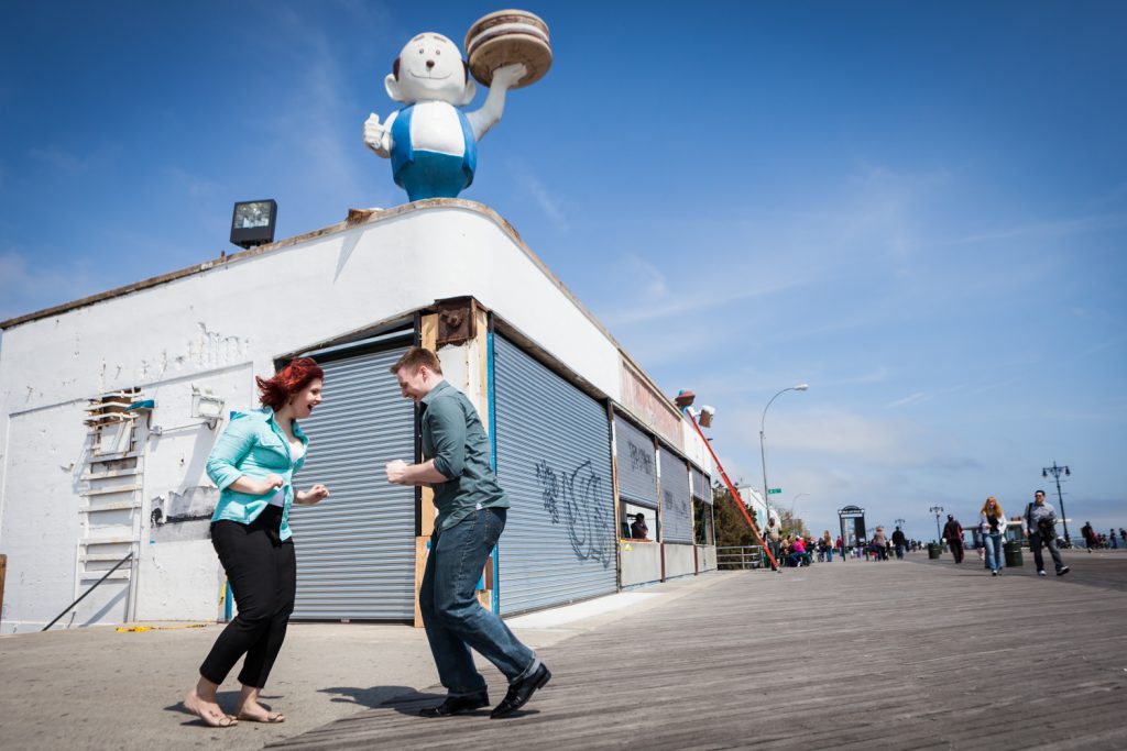 Coney Island engagement photos of couple dancing on boardwalk