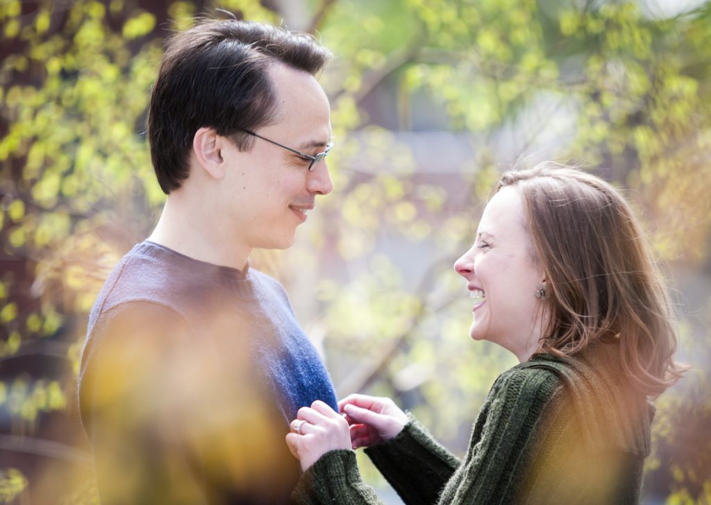 View through leaves of couple laughing during High Line engagement portrait session