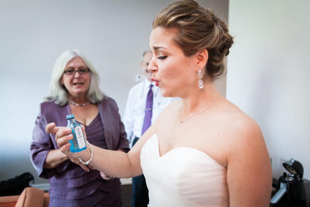 Bride taking a drink of gin from a small bottle before a Ravel Hotel Penthouse wedding