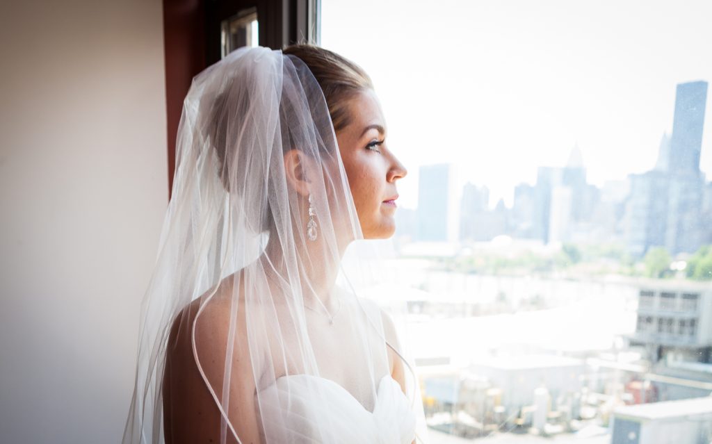 Portrait of a bride looking out window before her a Ravel Hotel Penthouse wedding