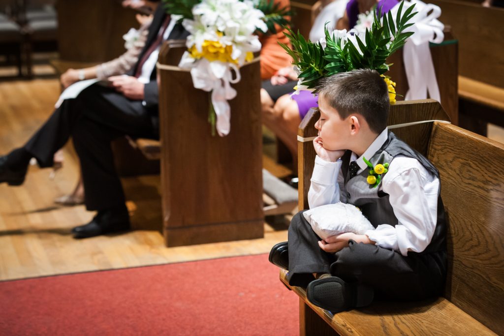 Little ring bearer asleep in pew during wedding ceremony