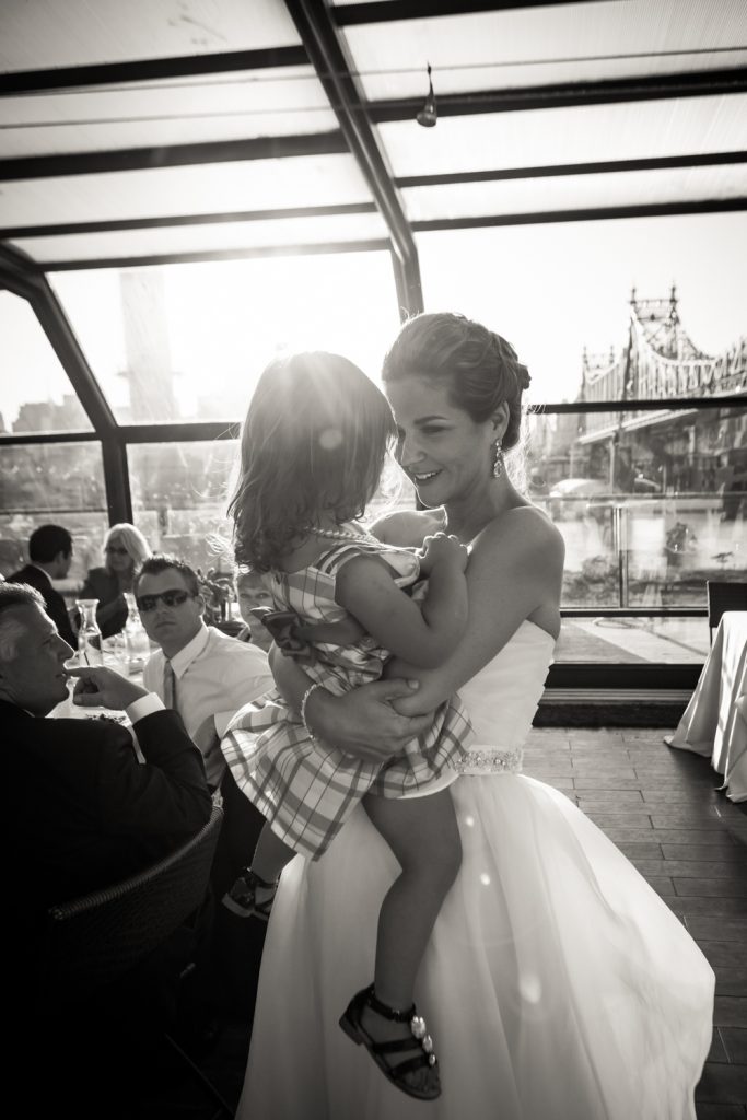 Bride holding little girl at a Ravel Hotel Penthouse wedding