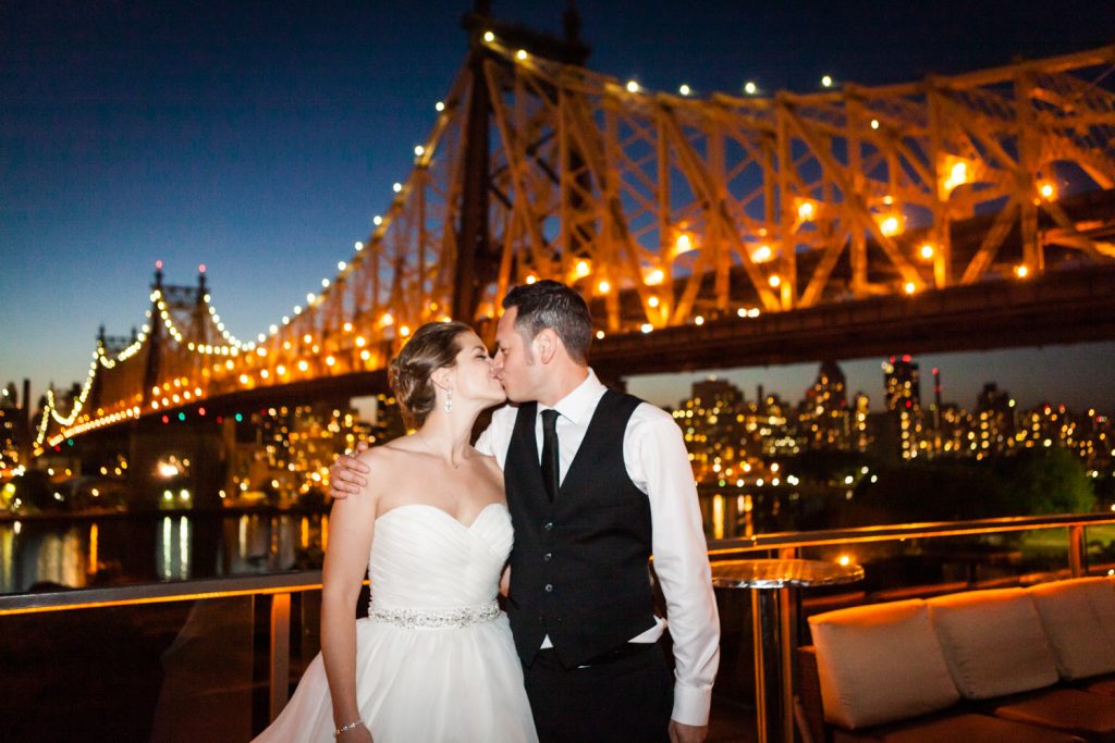 Bride and groom kissing with Queensborough Bridge in the background at a Ravel Hotel Penthouse wedding