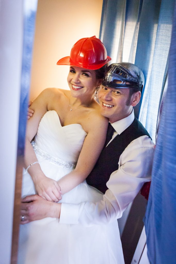 Bride and groom wearing silly hats in a photo booth at a Ravel Hotel Penthouse wedding