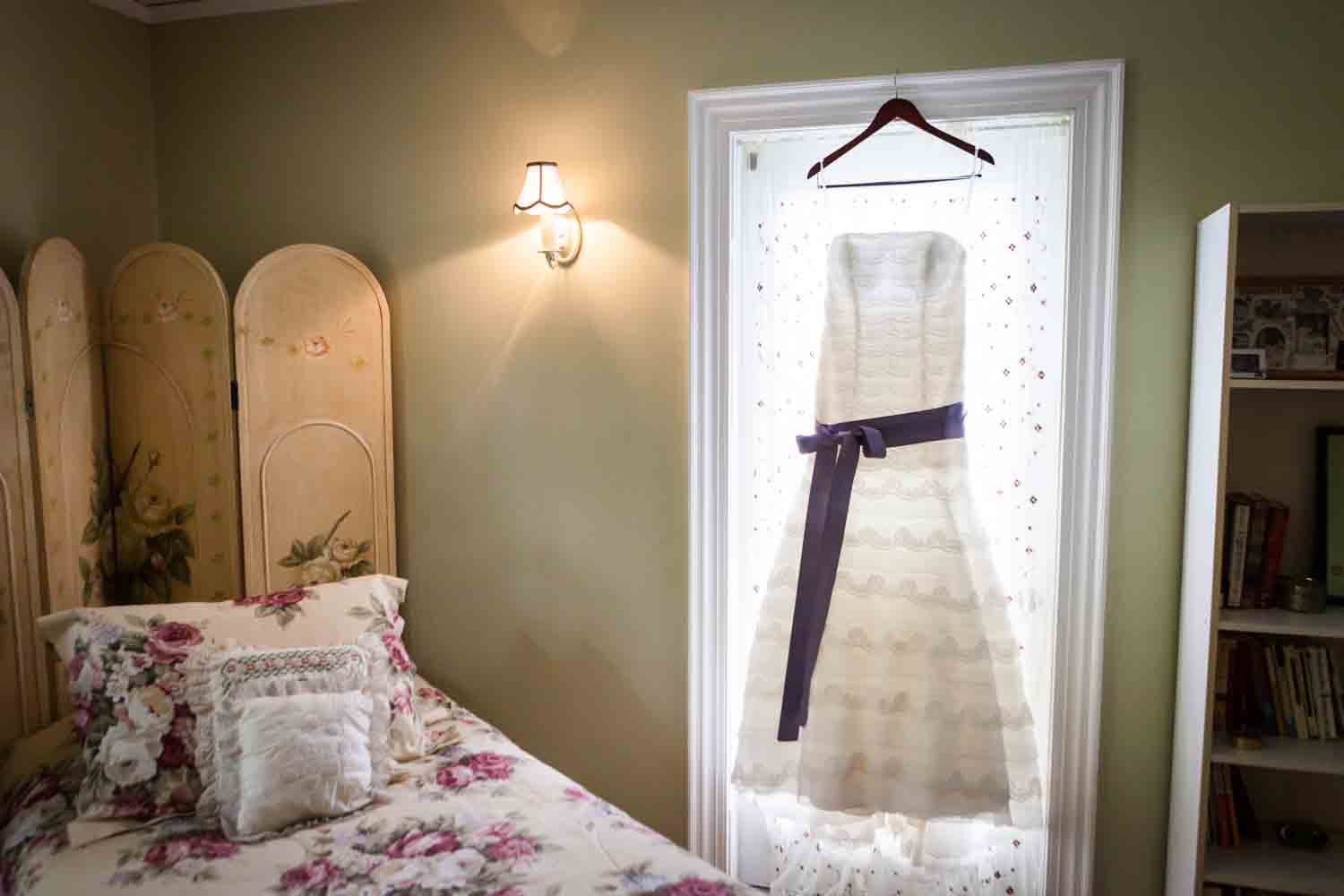 Wedding dress hanging in window of bedroom