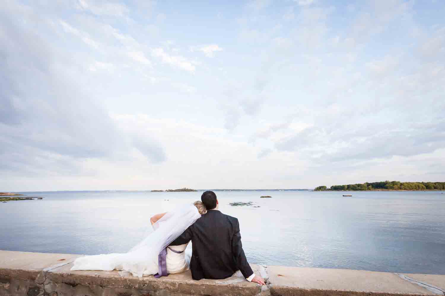 Bride and groom sitting on wall watching water at a Davenport Mansion wedding
