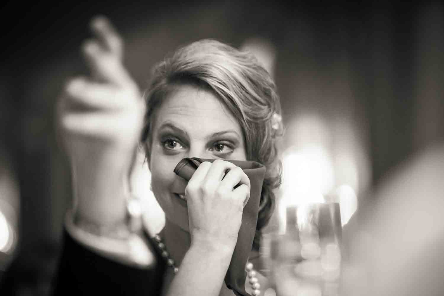 Black and white photo of bride wiping away tear
