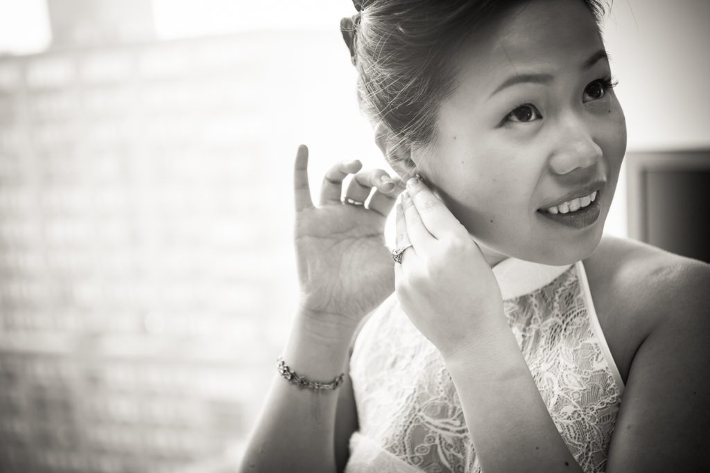 Black and white photo of bride putting in earring