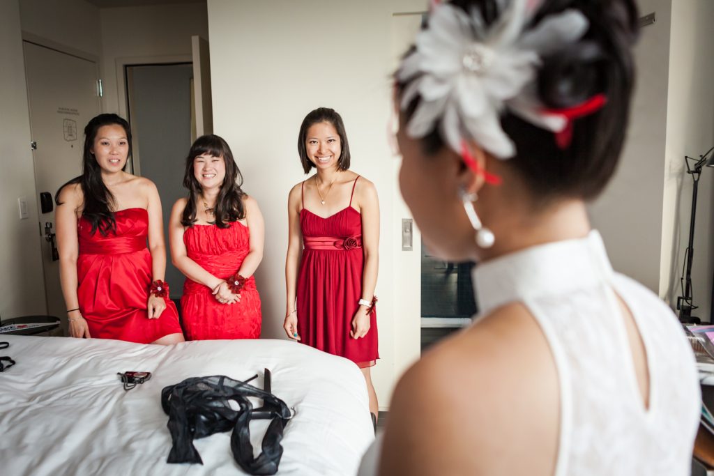 Three bridesmaids wearing red dresses looking at bride at a Merchant's House Museum wedding