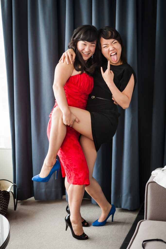 Two bridesmaids hugging and showing devil sign