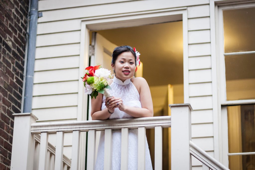 Bride with bouquet leaning on staircase railing at a Merchant's House Museum wedding