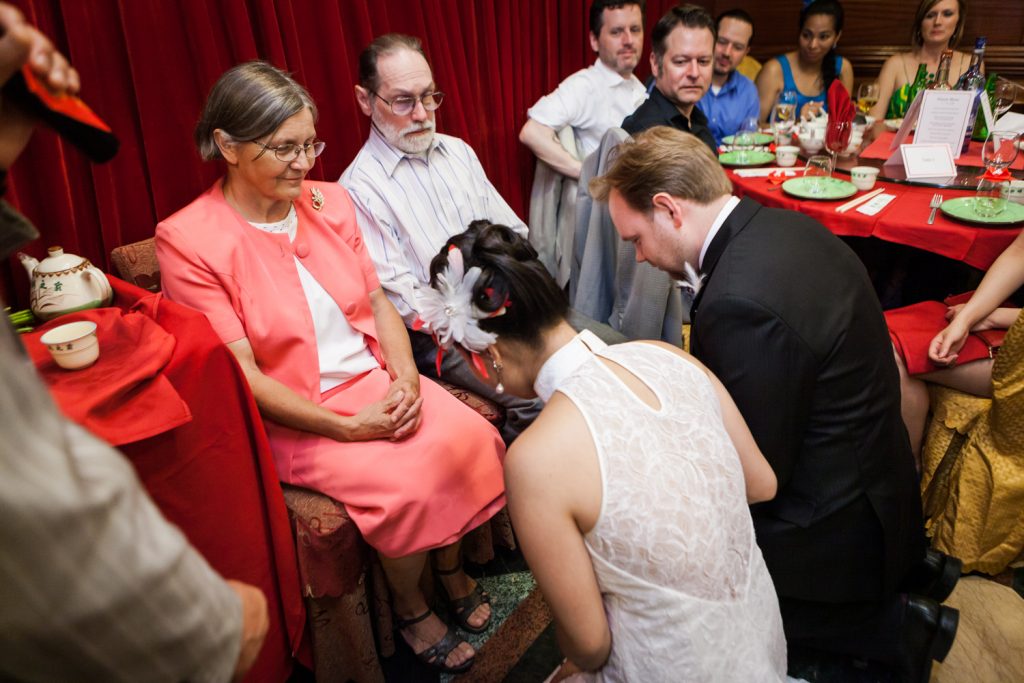 Bride and groom bowing to parents during tea ceremony at a Congee Village wedding reception