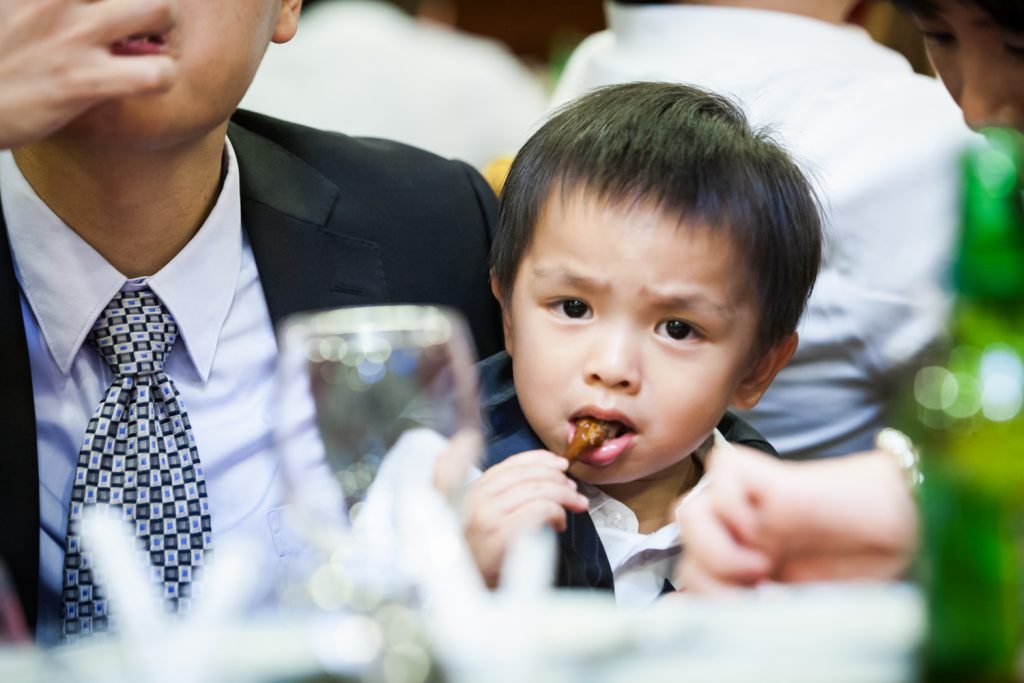 Little boy eating at a Congee Village wedding reception
