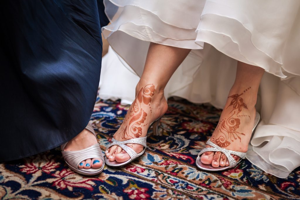 Close up on bride and maid of honor's feet with henna writing