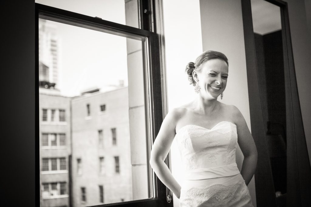 Black and white photo of bride in front of window