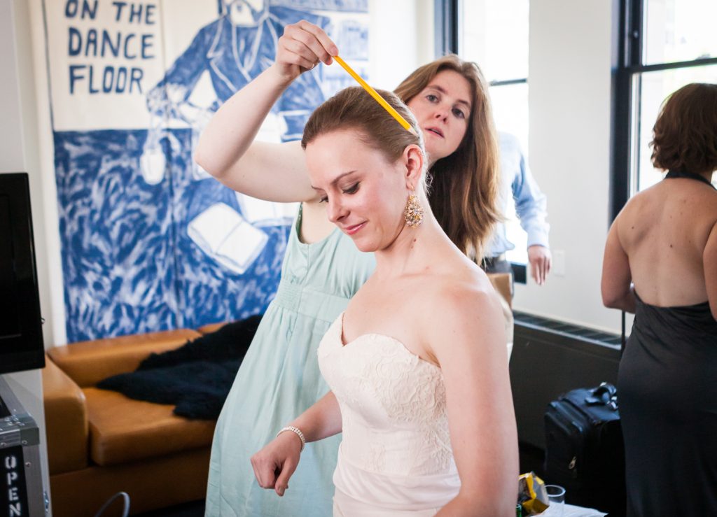 Woman smoothing hair of bride in hotel room