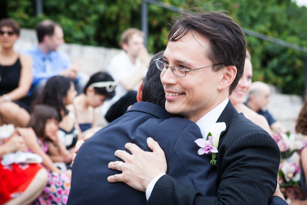 Groom hugging guest at a Brooklyn Bridge Park wedding