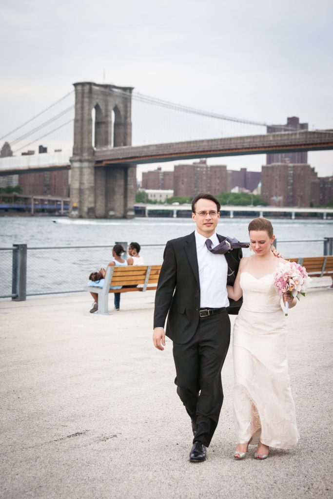 Bride and groom walking with Brooklyn Bridge in background at a Brooklyn Bridge Park wedding