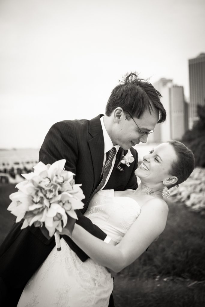 Black and white photo of groom dipping bride in Brooklyn Bridge Park